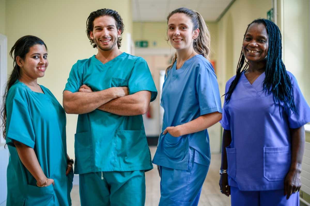 Male and female nurses in scrubs standing in a hallway.