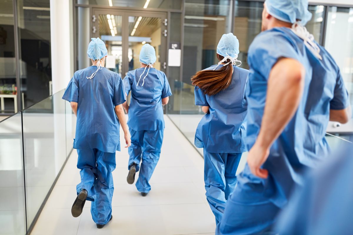 Nurses running down the hallway of a hospital, responding to alarms.