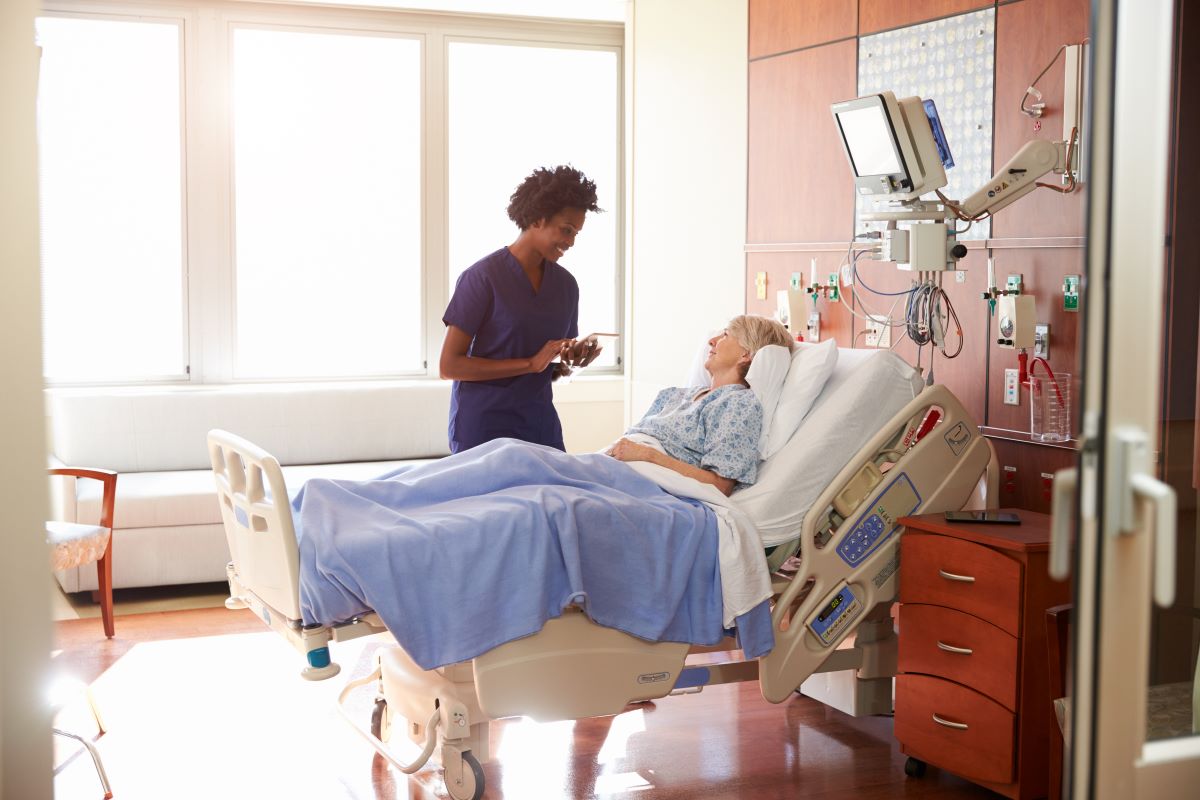A nurse in a patient's room, discussing treatment plans.