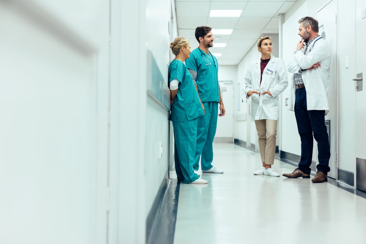 A couple of nurses discuss treatment plans with two physicians.