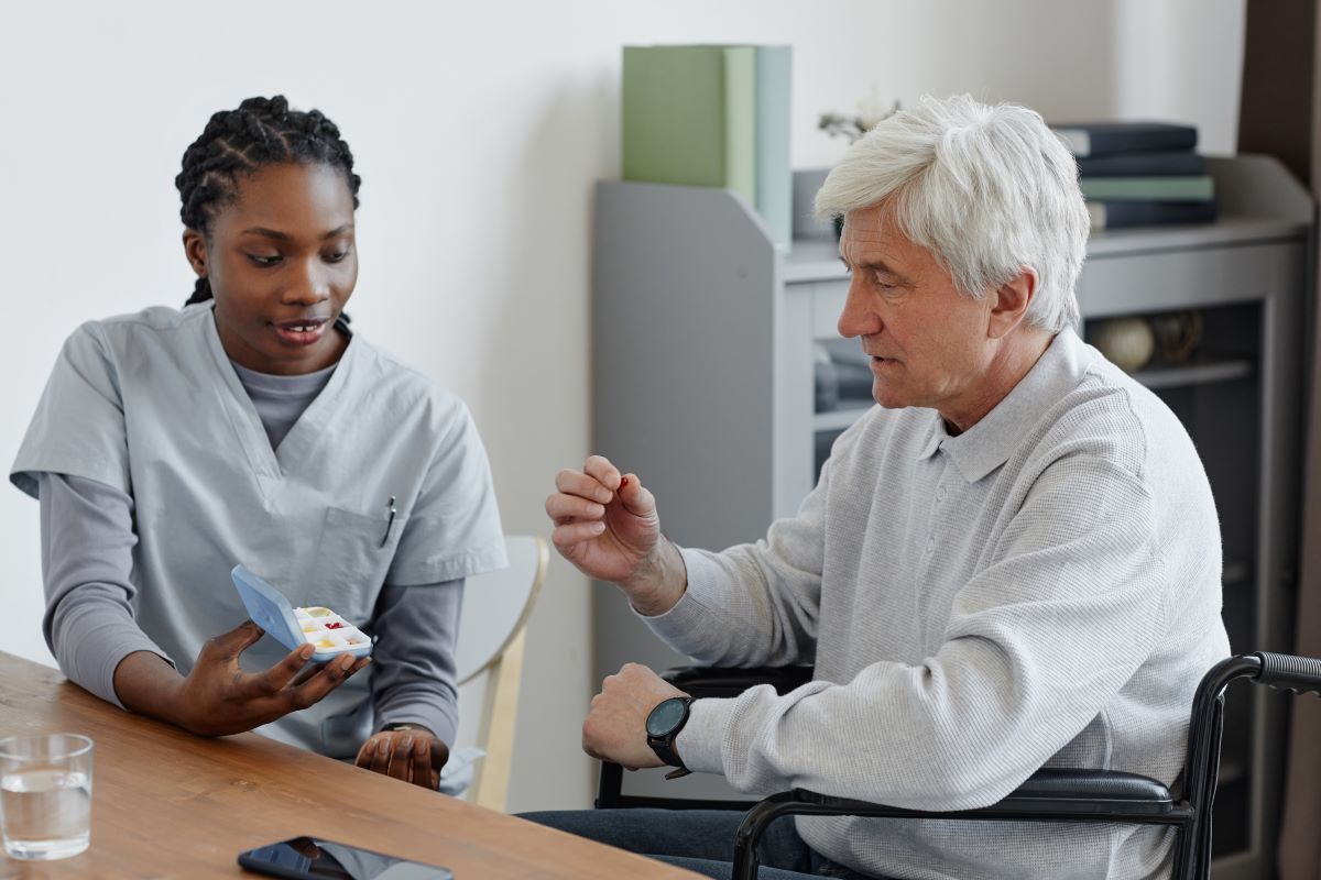 A nurse helps a nursing home resident with his medications.