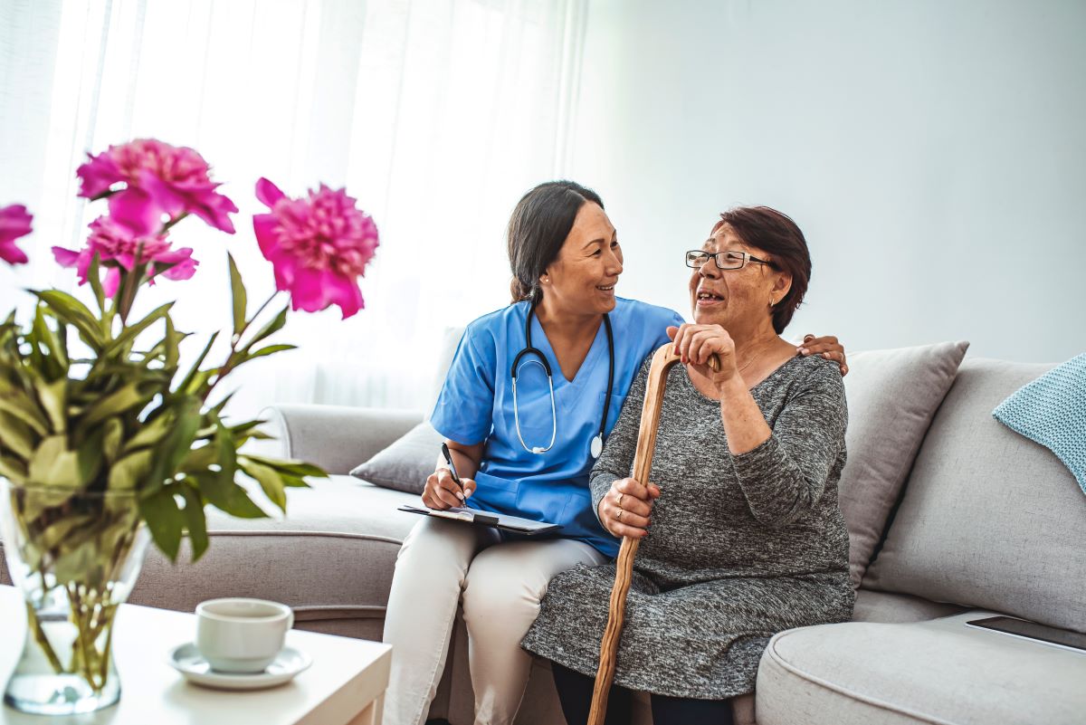 A nurse sits with a resident at a long-term care facility.