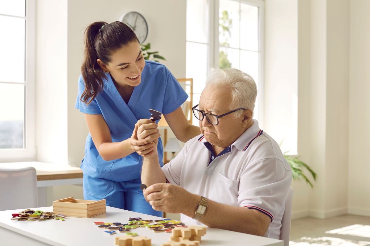 A nurse at a long-term care facility helps a resident with a puzzle.