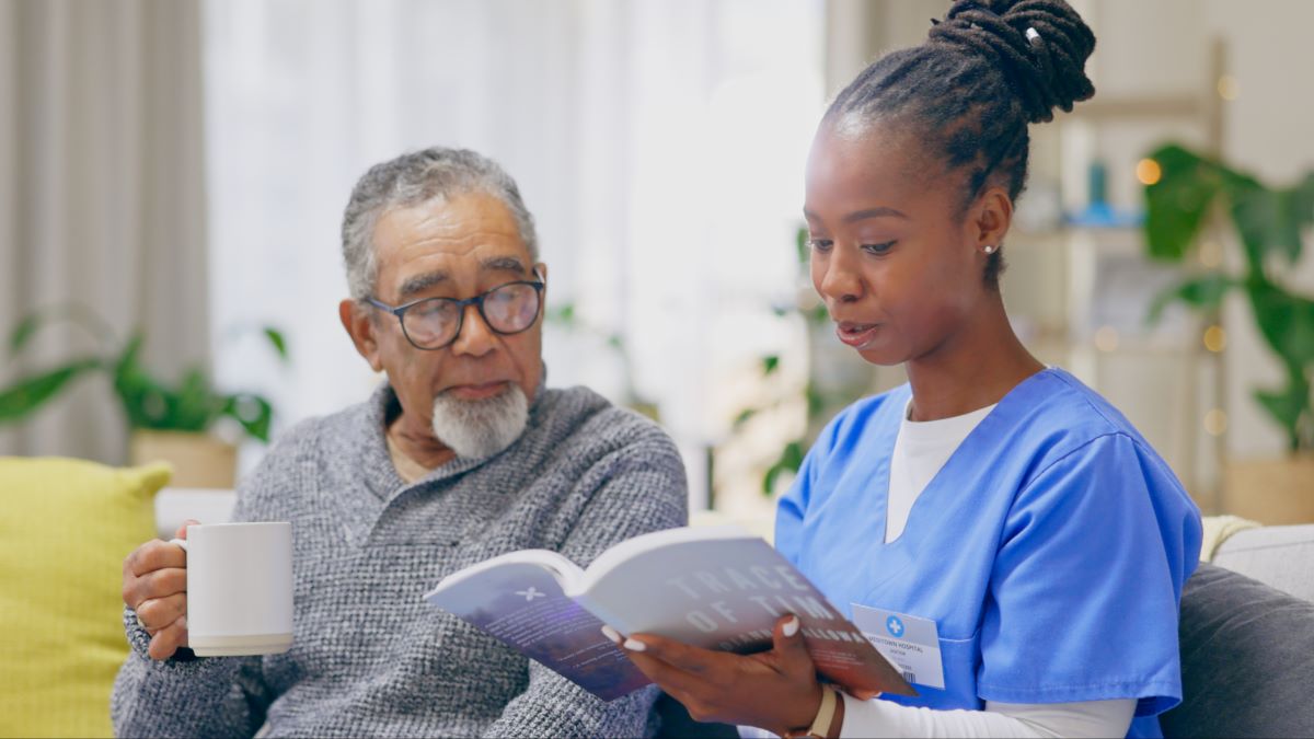 A hospice nurse reads a book to one of her patients.