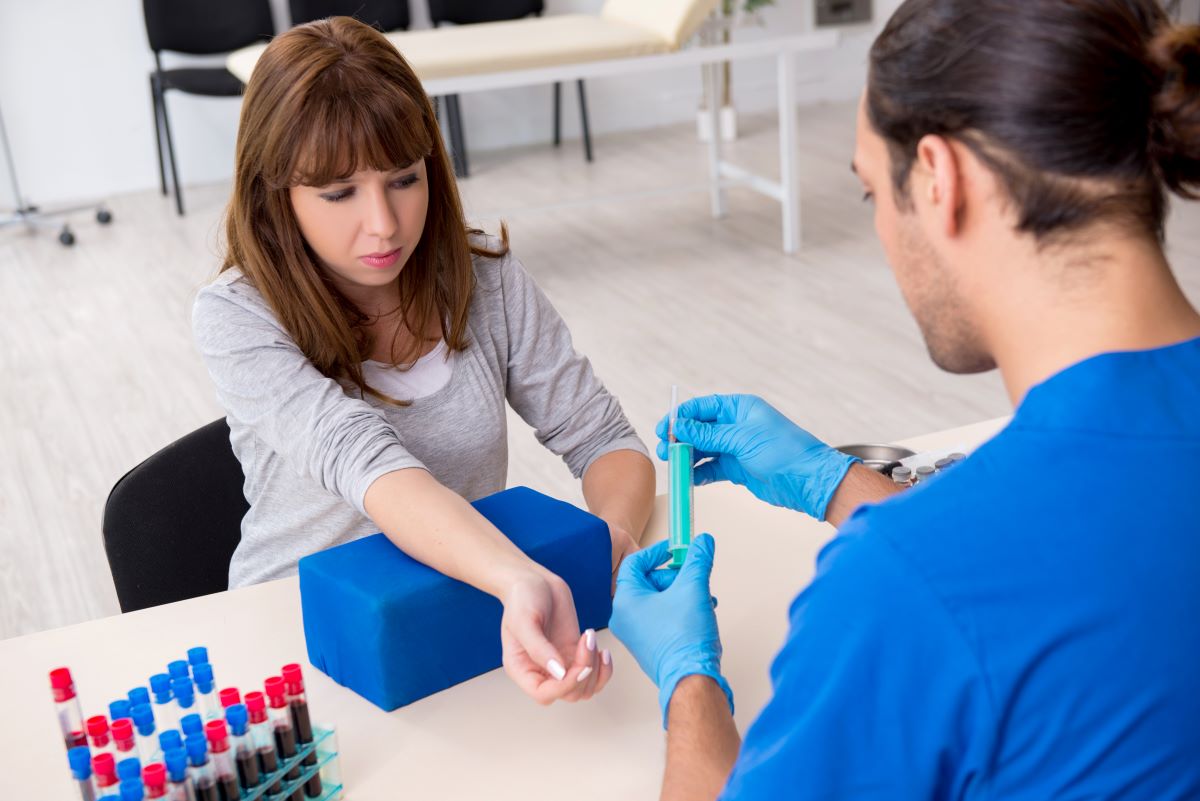 An outpatient nurse takes a blood sample from a patient.