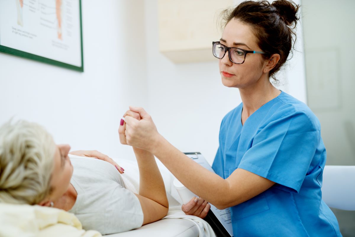 Outpatient nurse holding hand of patient in medical office