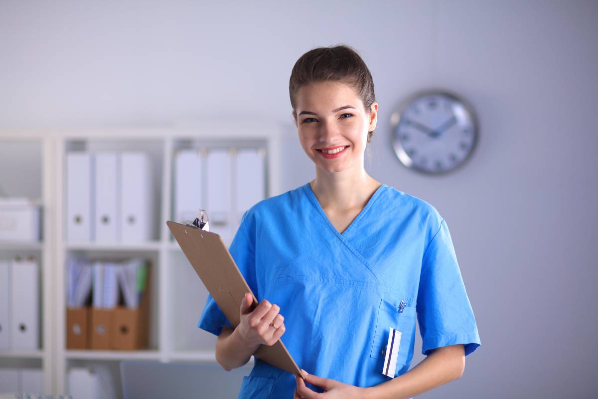 A nurse stands in a clinic with her PACU nurse resume.