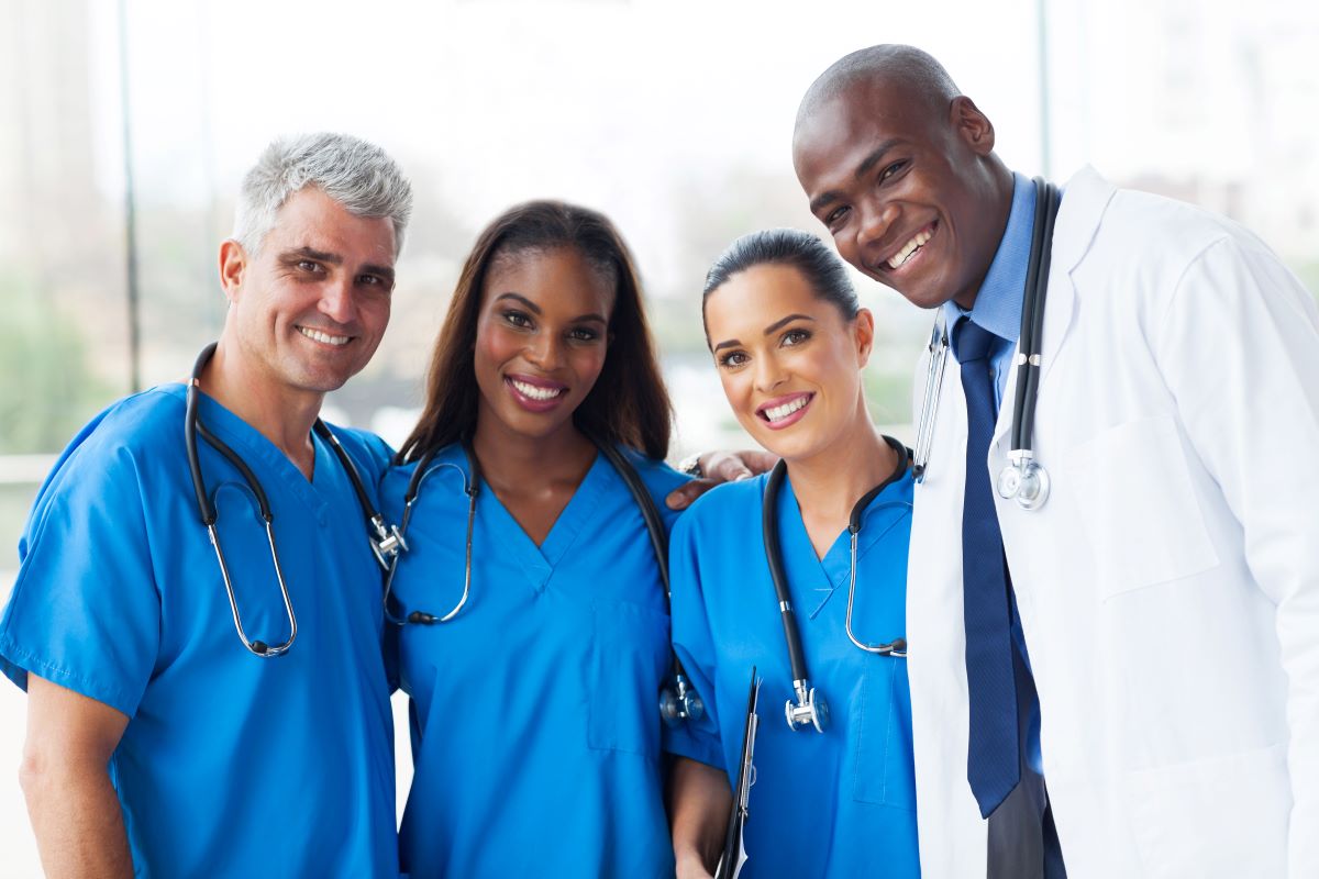 Three nurses and a physician smile at the camera.