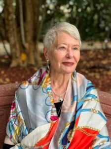 Woman with short gray hair wearing a colorful scarf and sitting outside