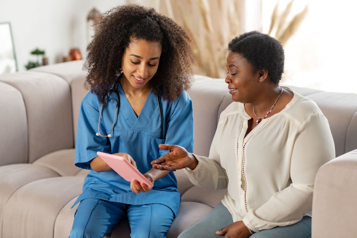 A nurse reviews health information on a tablet with a resident.