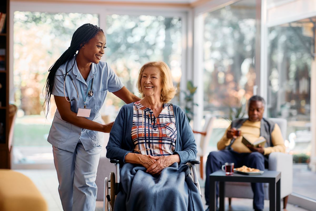 A CNA assists a nursing home resident who is in a wheelchair.