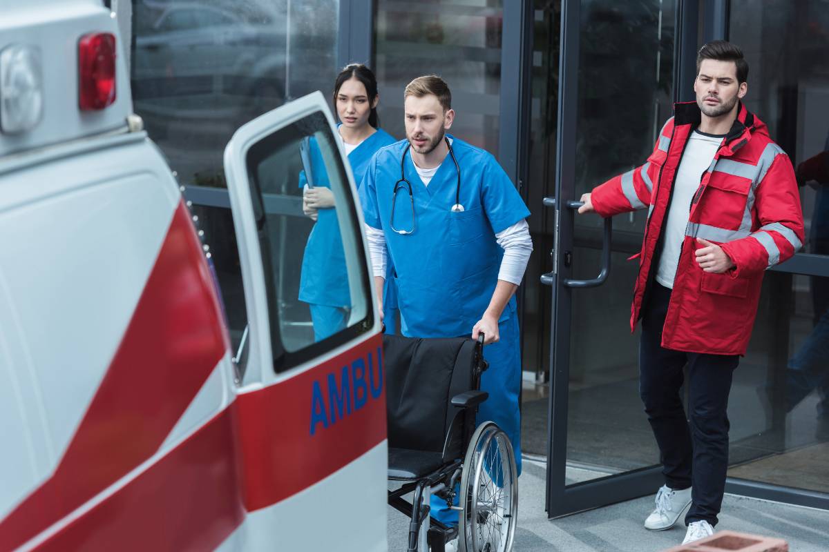 Healthcare professionals help an ambulance unload, demonstrating the difference between paramedic vs. RN roles.