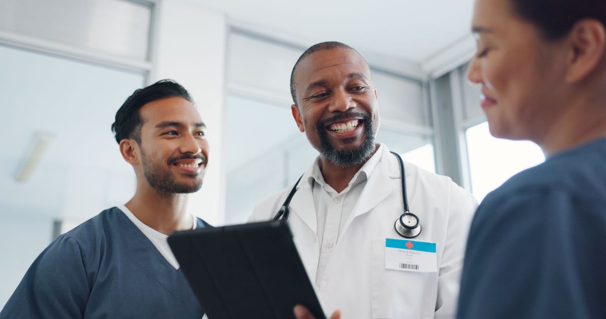 Two nurses have a jovial conversation with a physician.