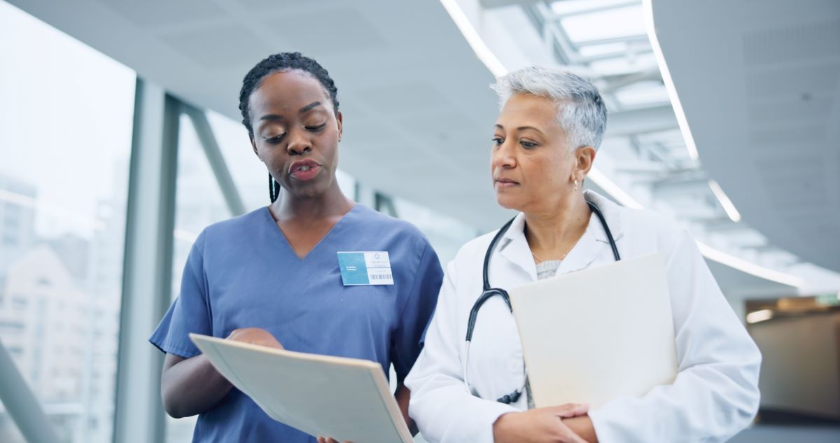 A nurse has a discussion with a physician, as they both look at a patient's chart.