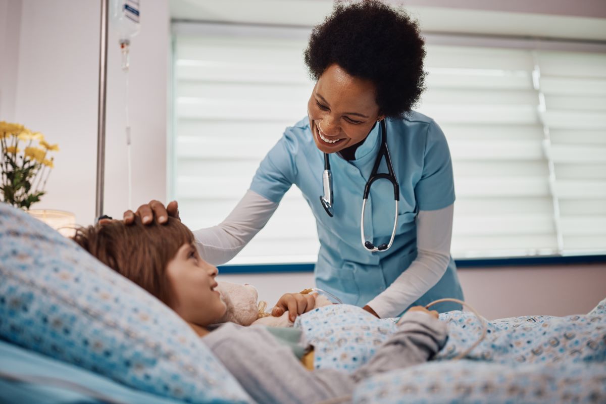 A nurse attends to a child in a hospital bed.