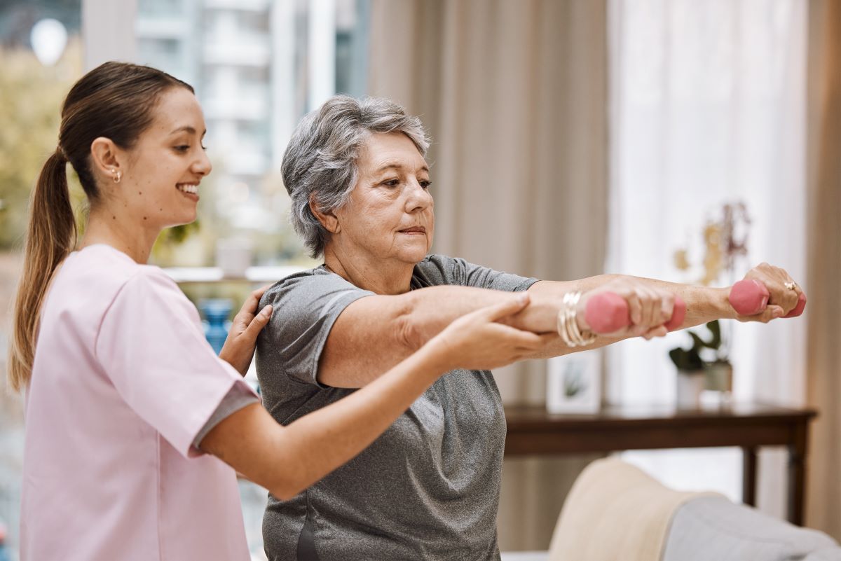 A nurse assists a nursing home resident with her exercises.