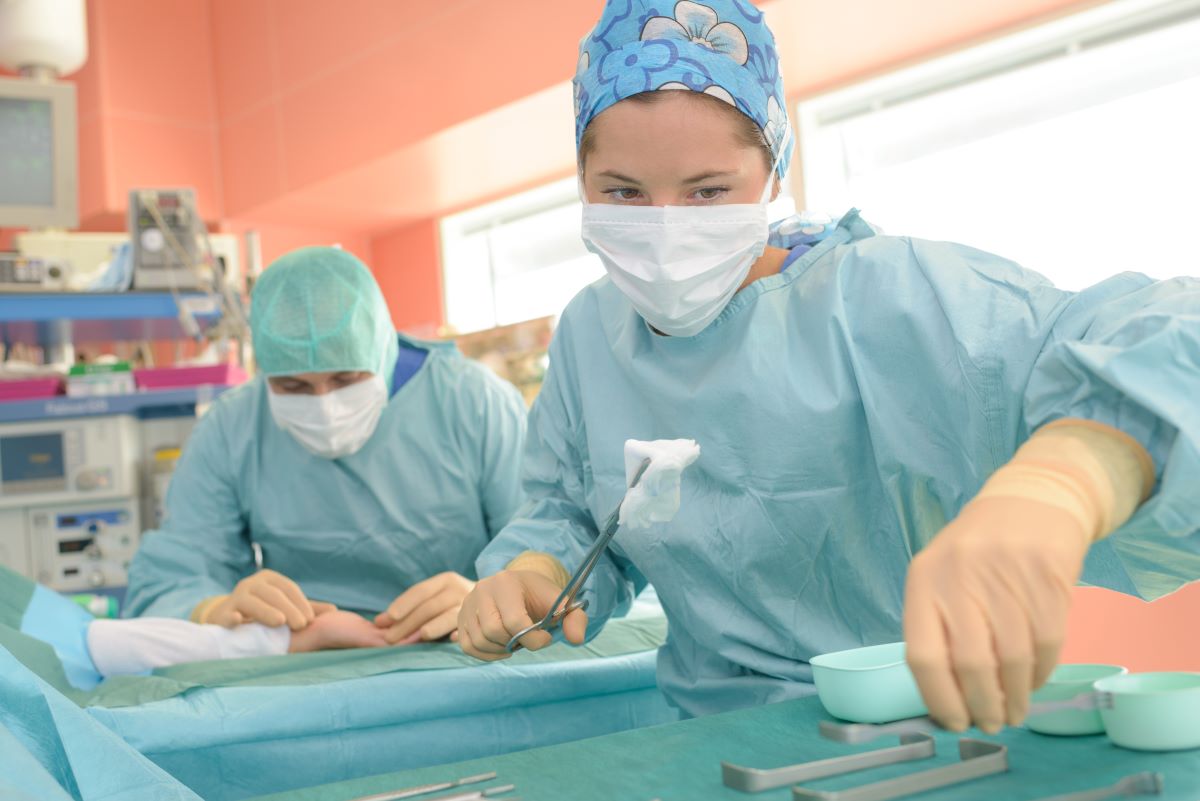 A surgical tech assists with a surgical procedure.