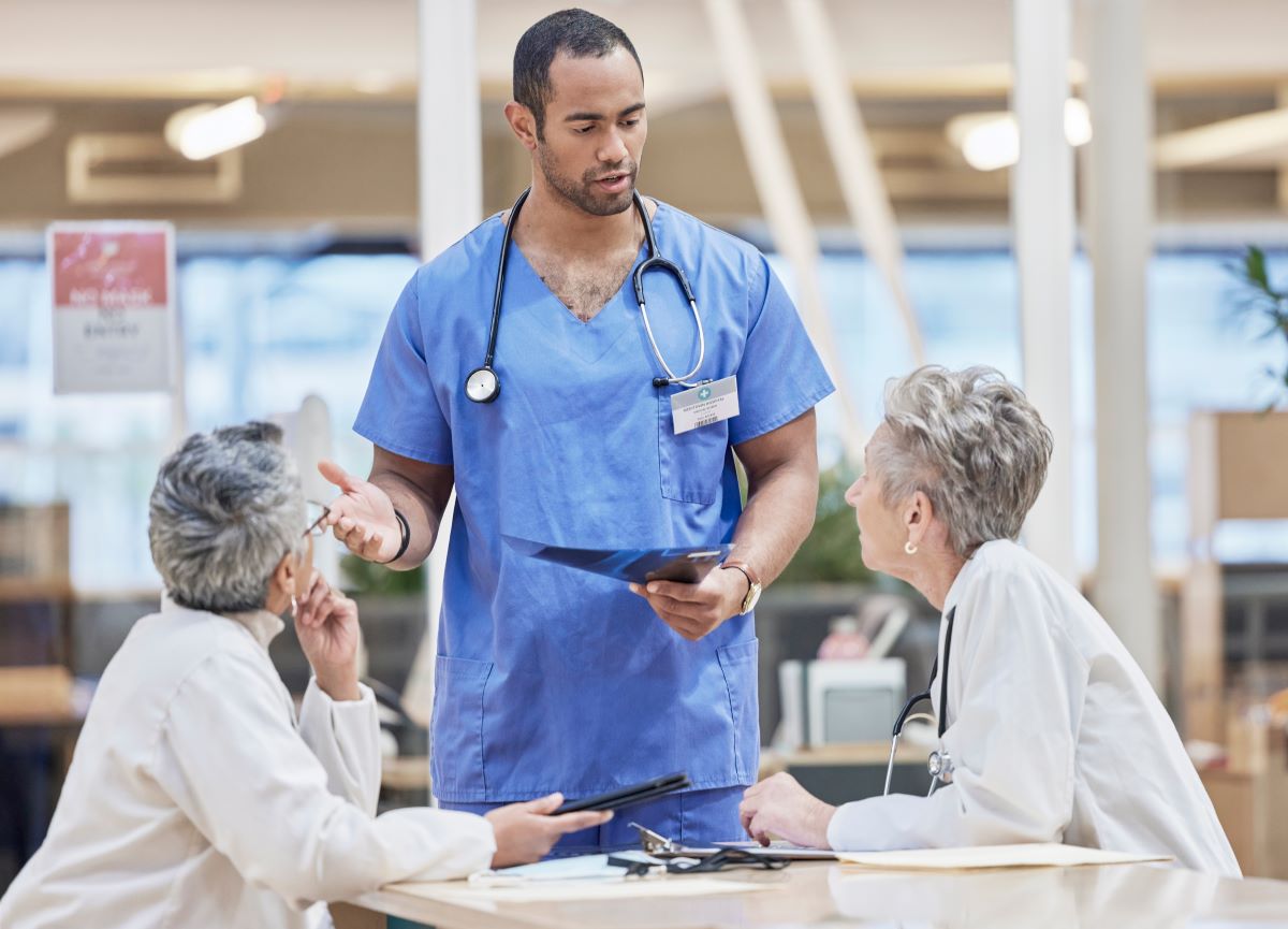 A charge nurse meets with two physicians.