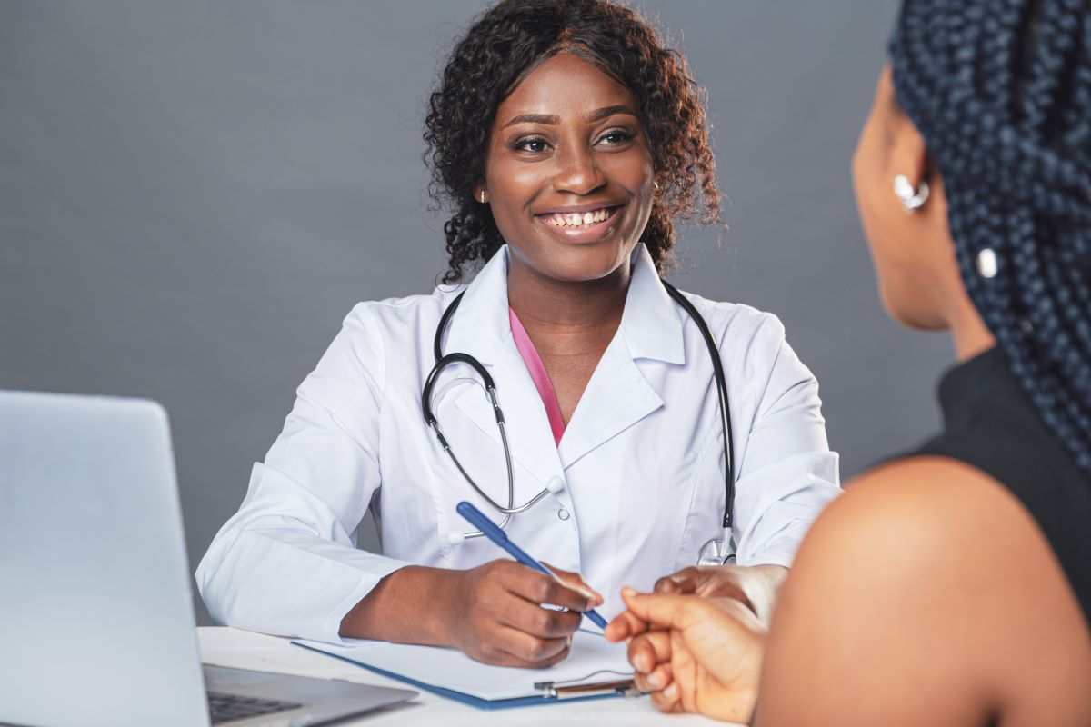 A nurse practitioner talks to one of her patients while taking notes.