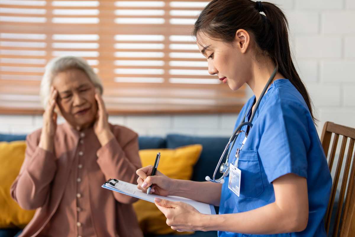 Neuro nurse with elderly patient who is holding her head.