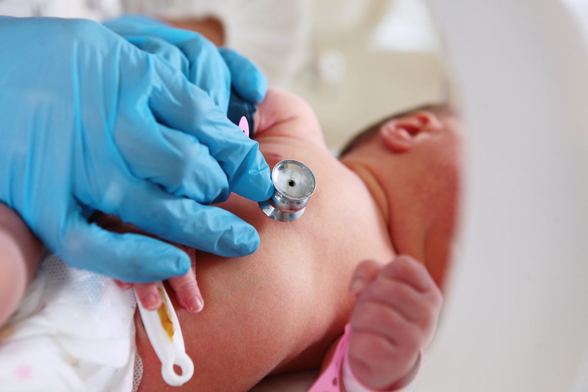 Close-up of a premature baby having its heart rate checked by a NICU nurse.