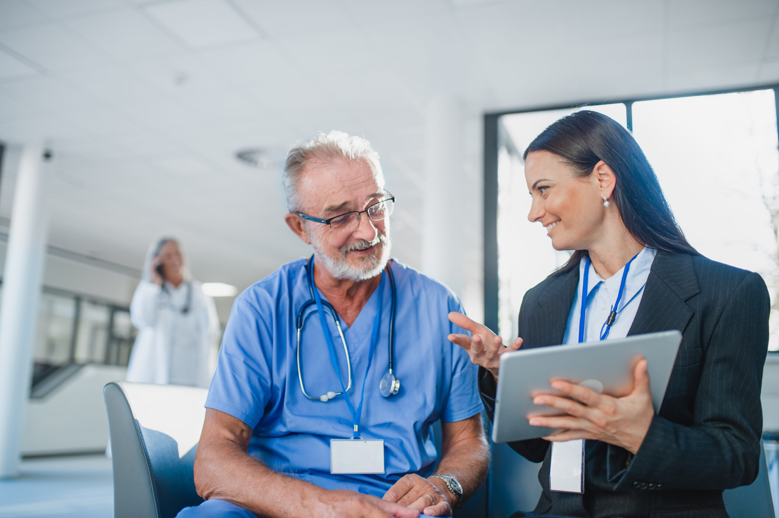 Nurse executive sitting with senior curse in a hospital and talking.