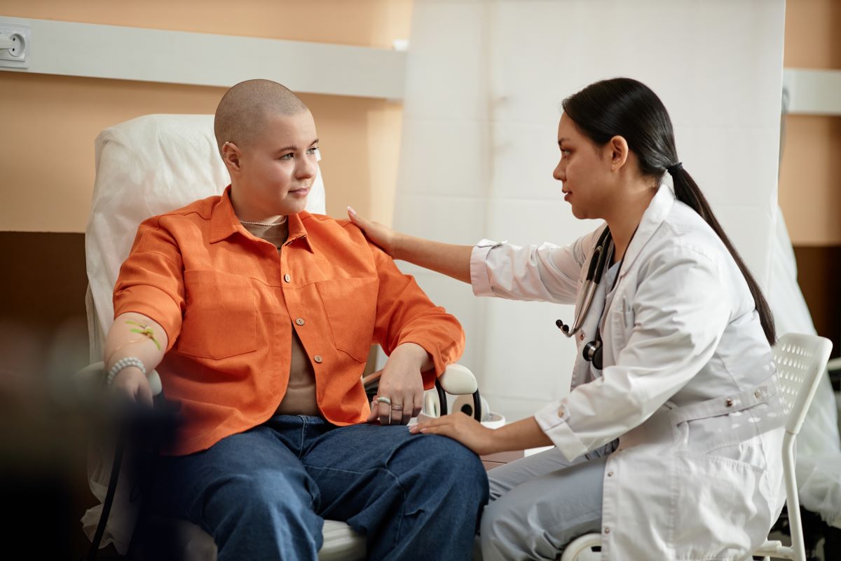 An oncology nurse consoles one of her patients who is undergoing chemotherapy.