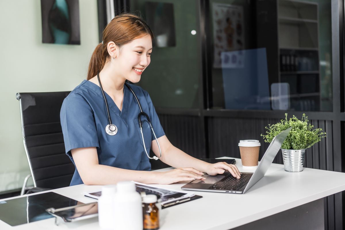 An advice nurse sits at her desk and assists a patient via web video.