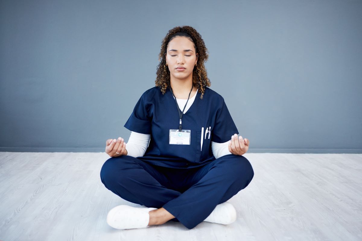 A nurse meditates, one effective way of managing emotions at work.