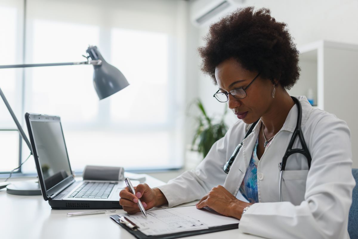 A nurse practitioner looks at her patient chart as she sits at her desk.