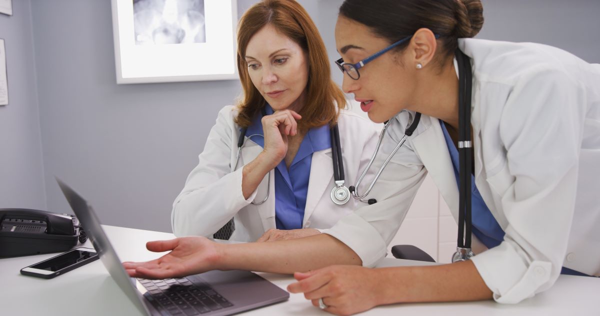 A physician's assistant and her supervising physician discuss a patient's chart.