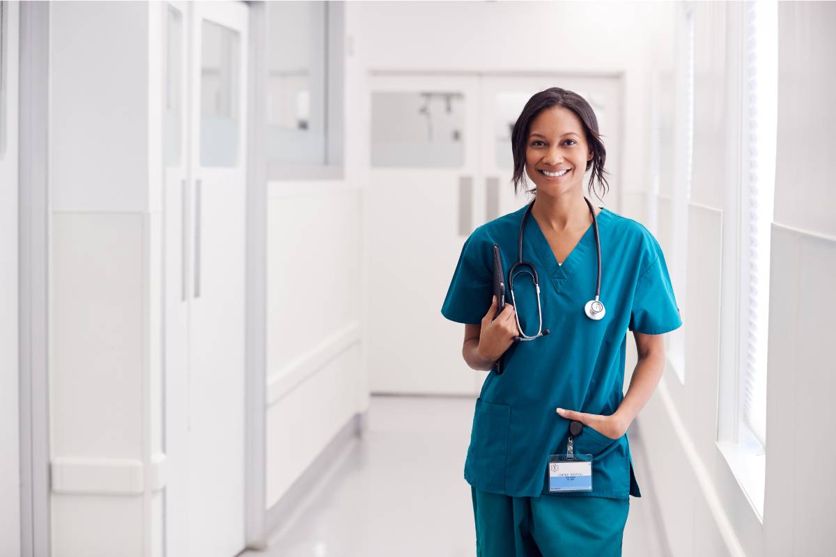 A GI nurse in teal scrubs stands in a hallway.