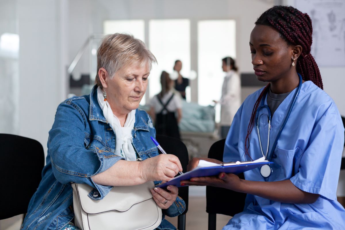 A patient signs off on a form presented to her by a nurse in the hospital discharge lounge.