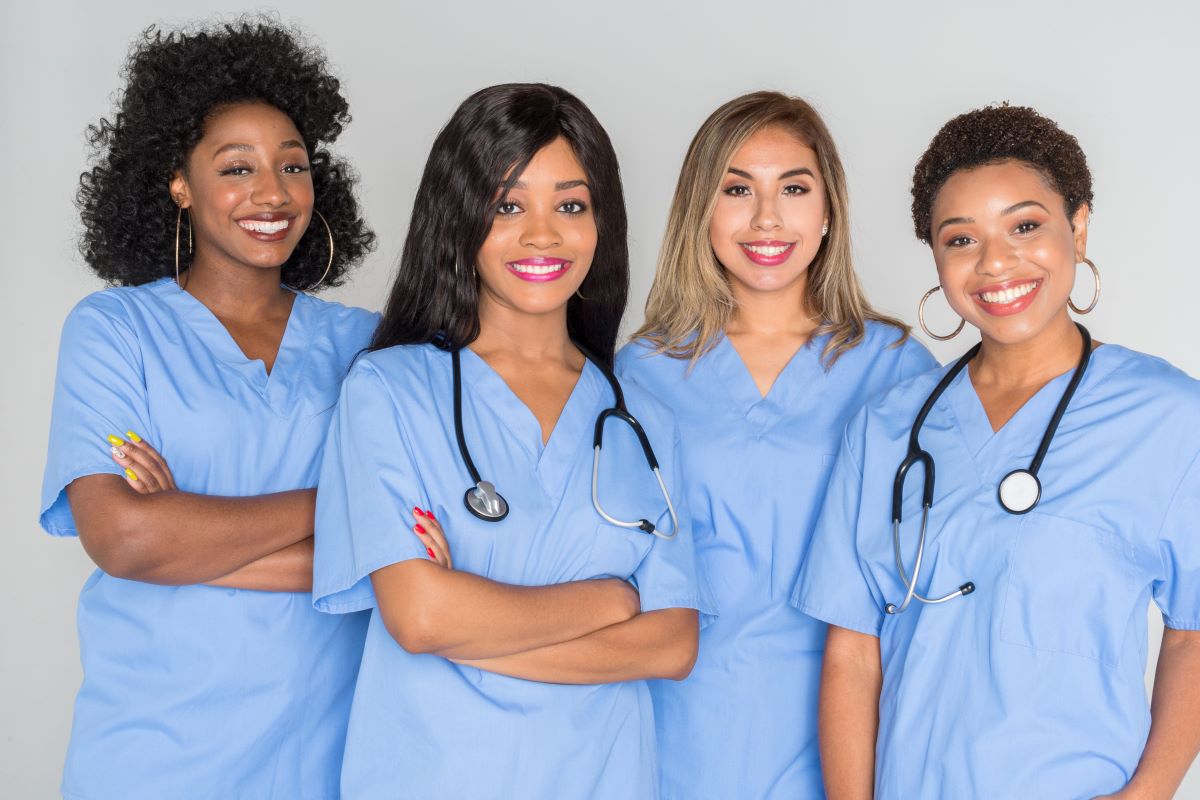 A group of four nurses, smiling at the camera.