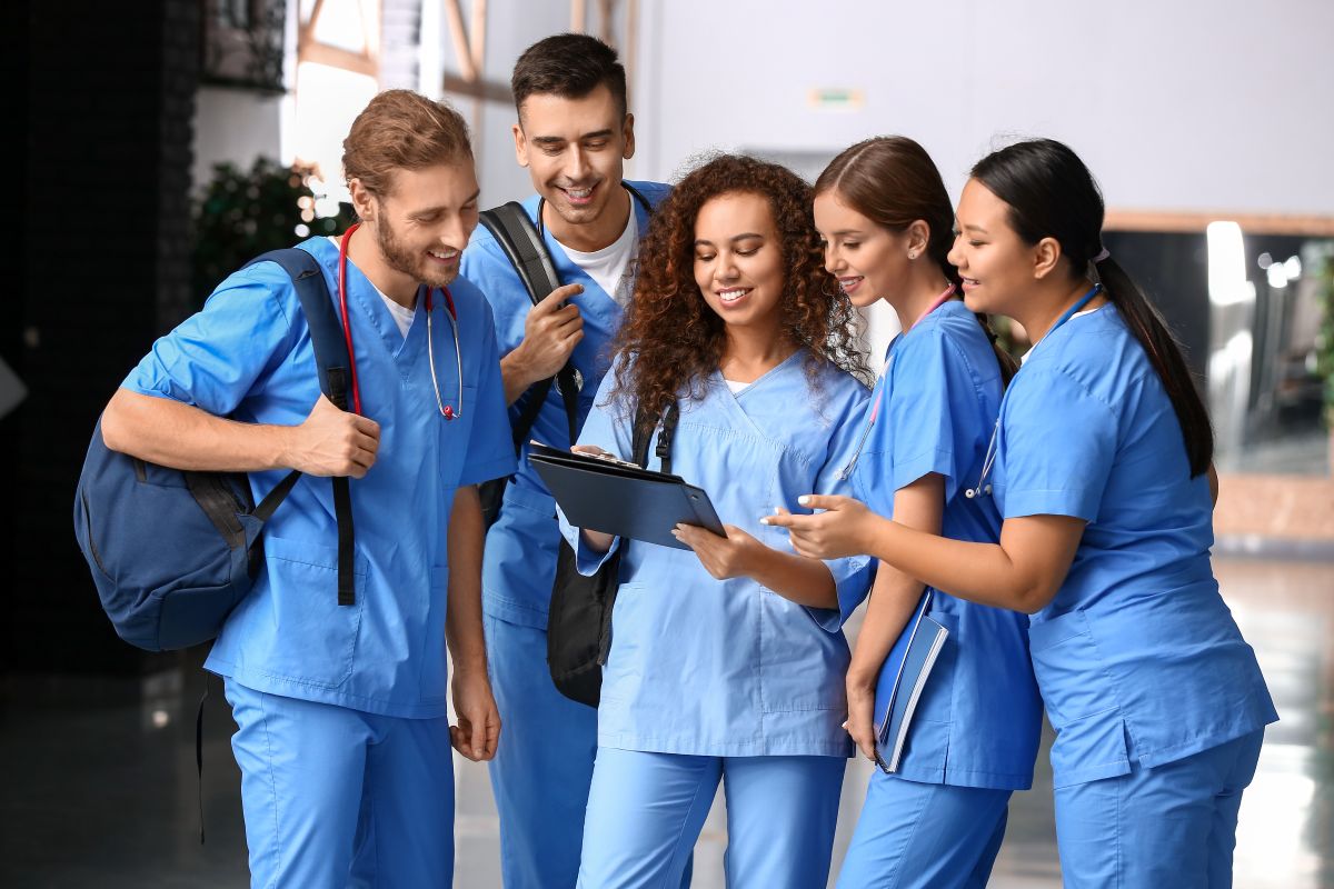 Five nurses discussing something they see on a tablet computer.