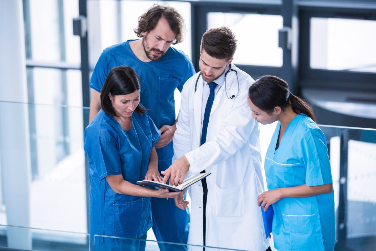 A physician and three nurses look over a patient's chart together.