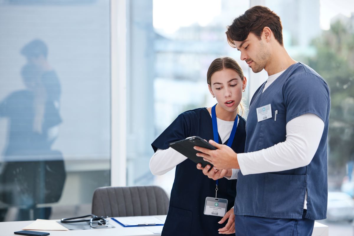 A nurse manager and coworker discuss a patient's chart.