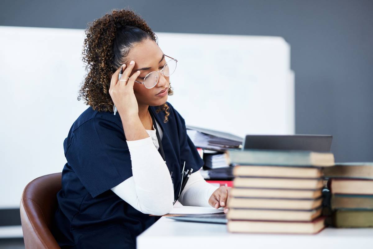 A nurse looking up nurse practitioner schooling requirements at a desk.