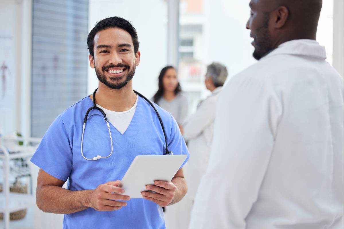 A nursing supervisor wearing blue scrubs and holding a clipboard.