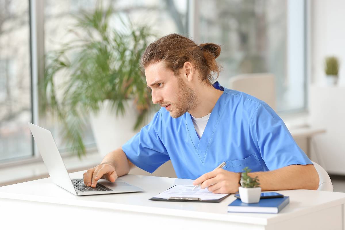 A nurse writes his own personal philosophy of nursing on a laptop.