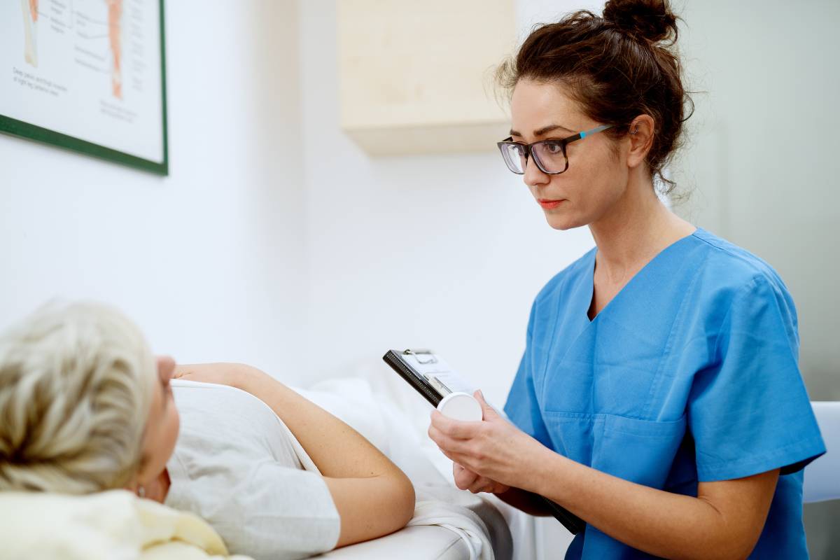 A nurse practitioner with WHNP-BC credentials cares for a patient laying on an exam table.