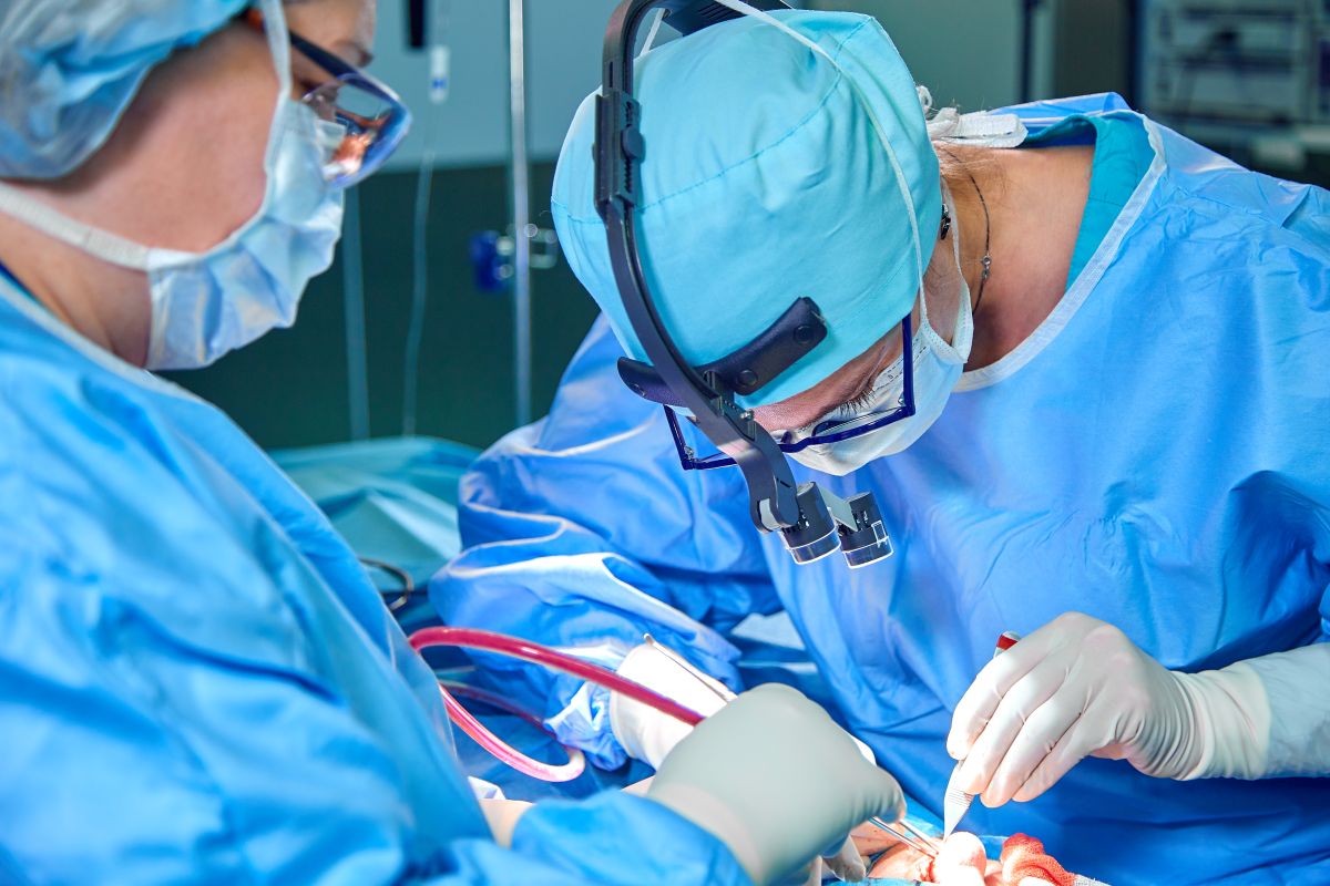 A cardiac nurse assists a surgeon with a heart surgery procedure.