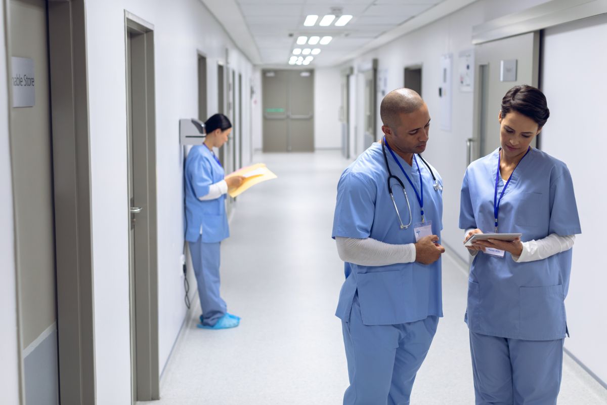 Connecticut nurses discuss something on a patient file in the hallway of a hospital.