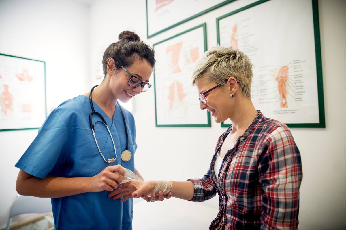 A CWCN nurse wraps a bandage on a patient's wrist.