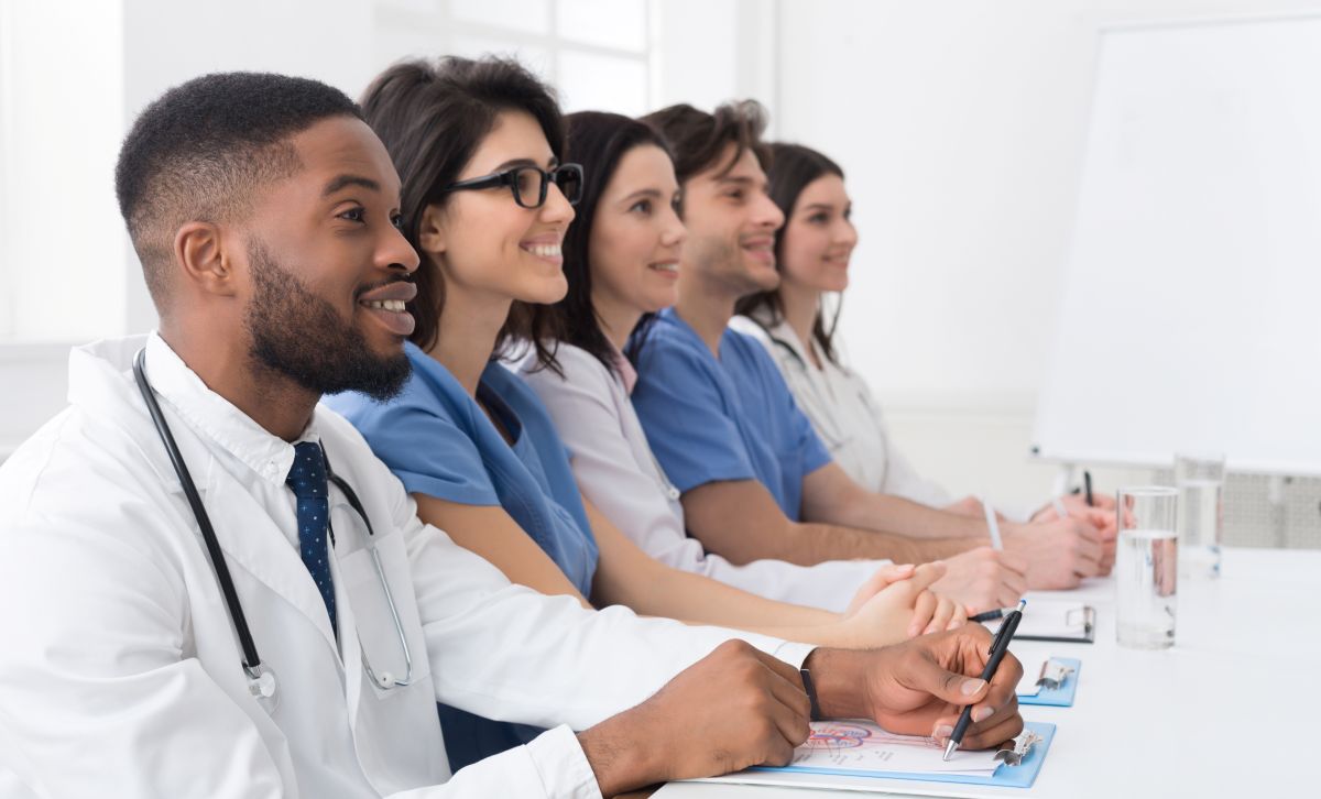 A group of doctors and nursing sit for a healthcare staff training session.