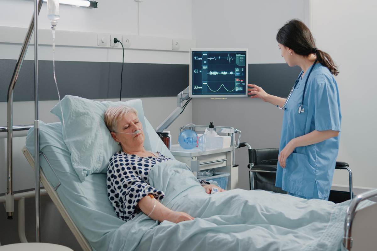 A nurse with telemetry certification reads a monitor in a patient's room.