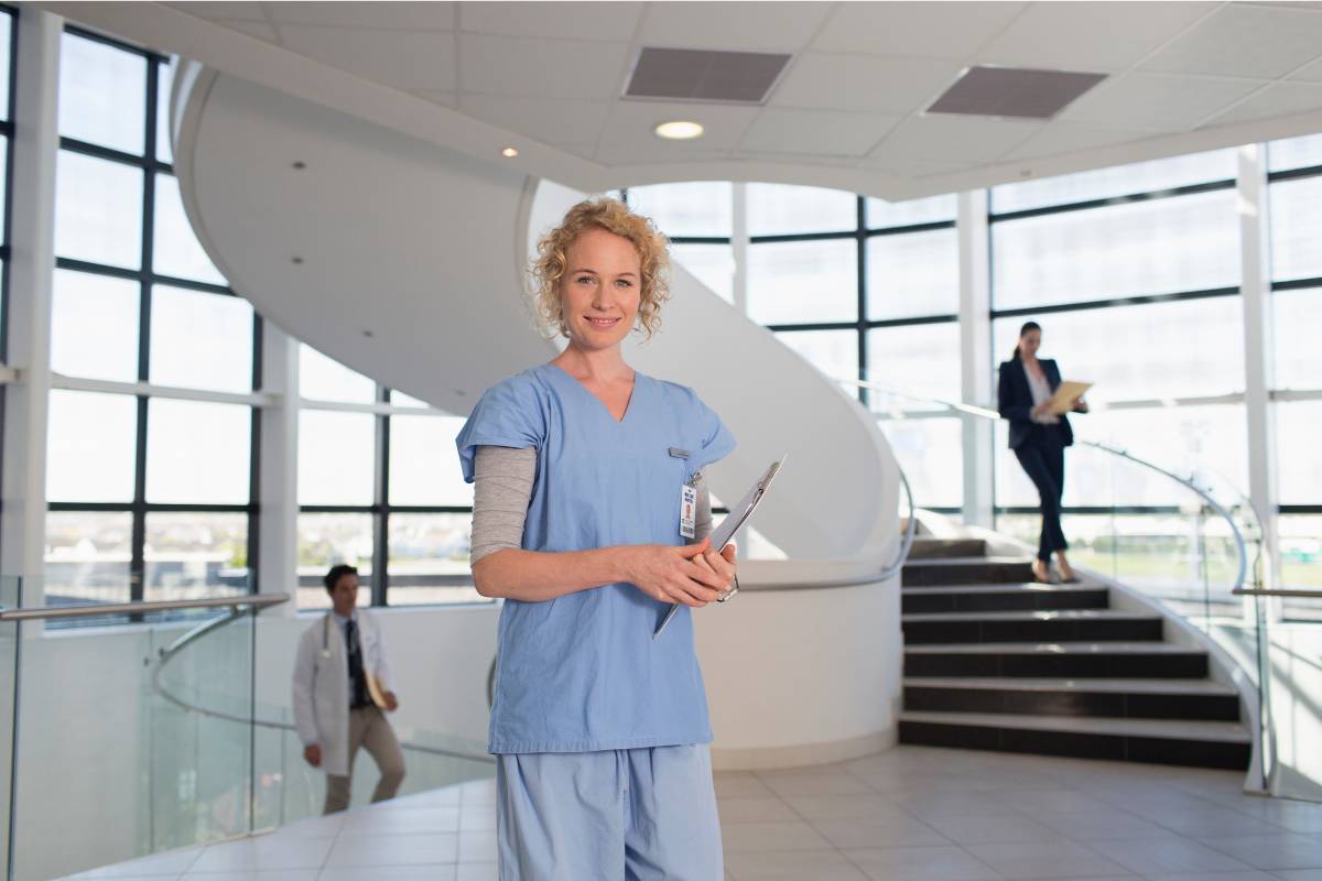 A nurse poses for a photo in a hospital while discussing how to be an RN in NY.