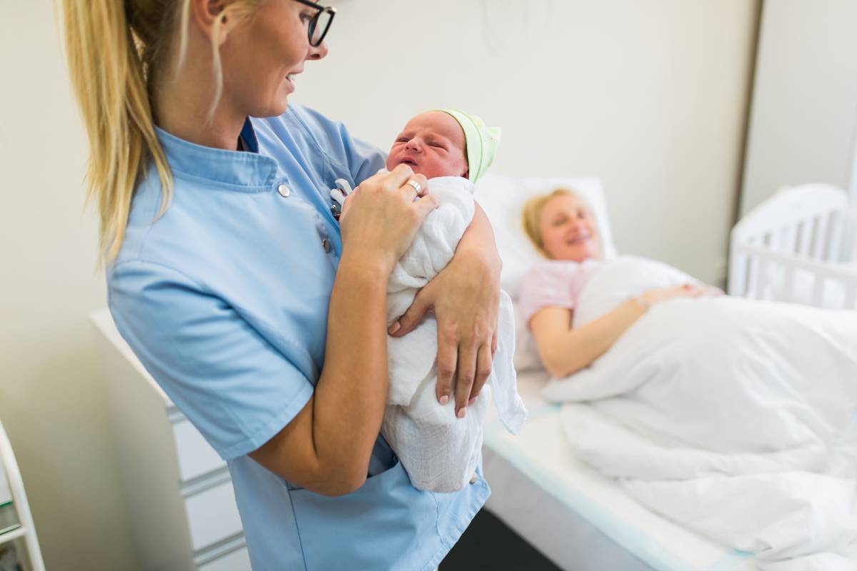 A LRN nurse holds a newborn in a hospital room.